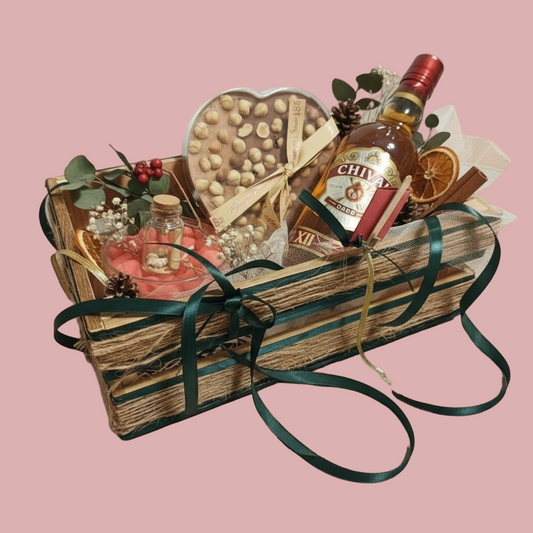 Gift basket with a bottle of Chivas Regal whiskey, chocolates, and other items on a tiled floor.